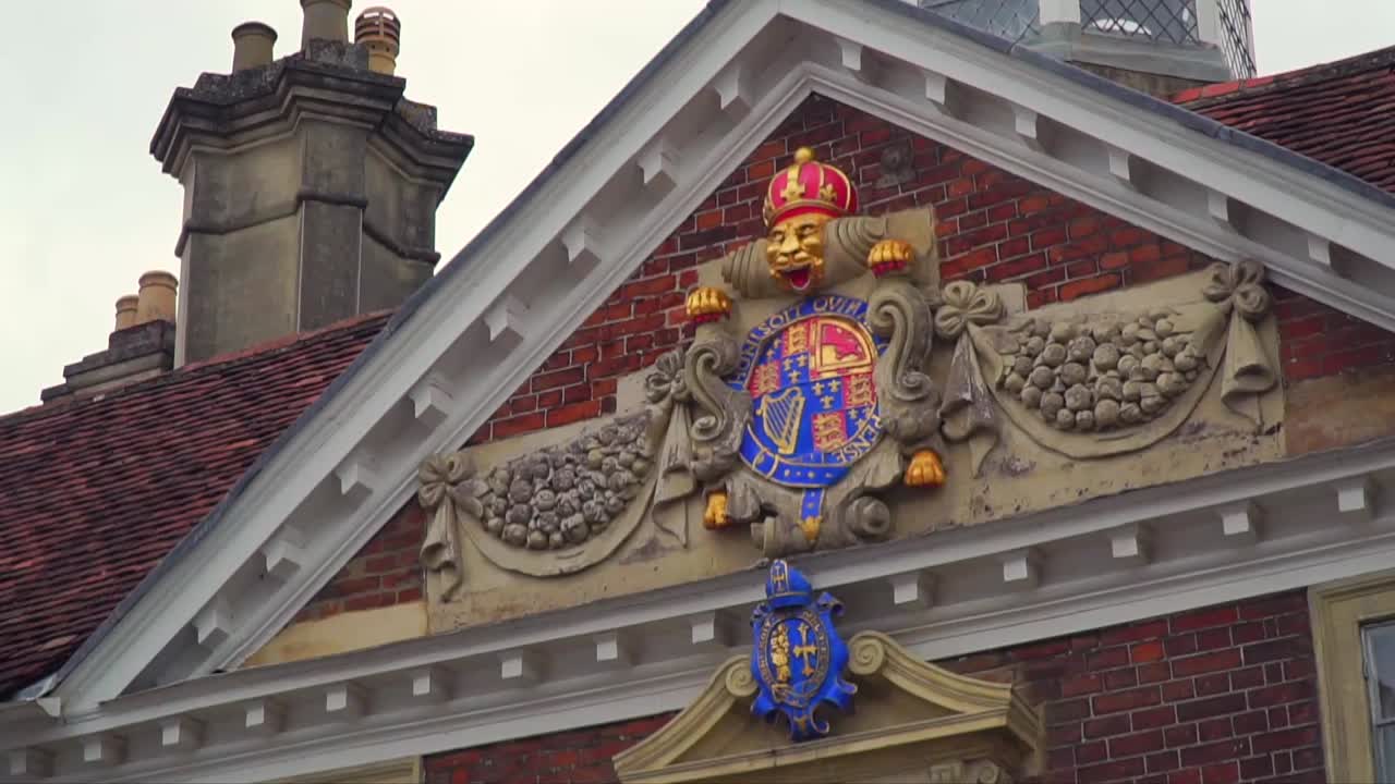 Close-up of a vibrant royal coat of arms and sculptural details above the entrance of a historic brick building in Salisbury, Wiltshire, England.