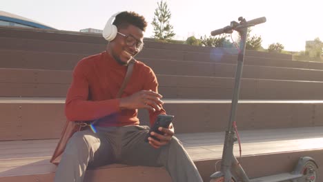 energetic black man enjoying music in headphones outdoors