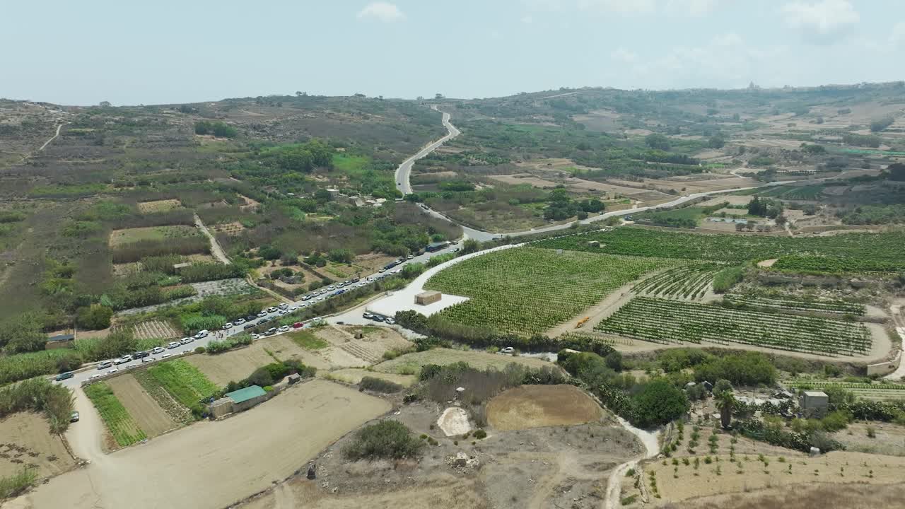 las imágenes de drones ofrecen una amplia vista aérea de una carretera sinuosa que atraviesa extensas tierras de cultivo y exuberante vegetación en un paisaje rural.