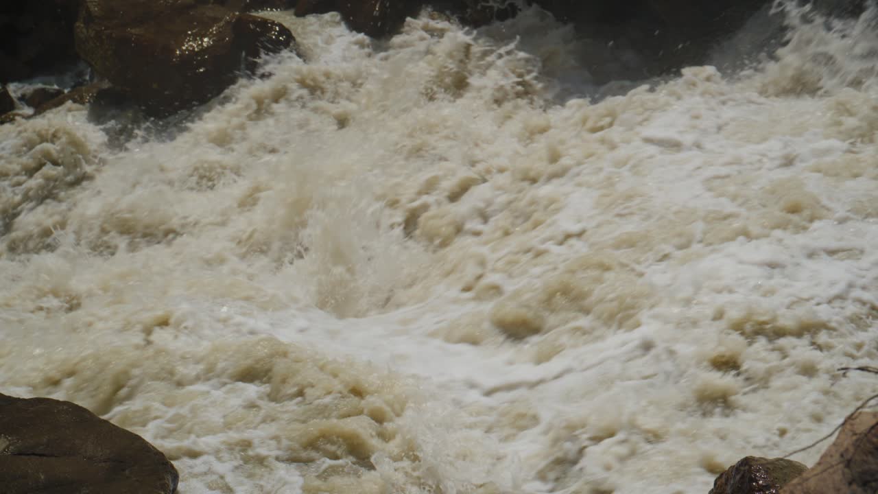 Acqua Impetuosa del Fiume si Infrange sulle Rocce, Creando Schiuma Bianca. Il Flusso Turbolento Mostra una Potente Forza Naturale. Ideale per Temi di Avventura, Natura o Condizioni Meteorologiche Estreme. Nessuna Persona Presente