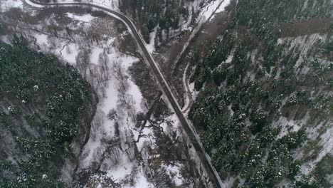 Luftaufnahme-Von-Autos,-Die-Auf-Der-Winterlandstraße-Im-Verschneiten-Wald-Fahren