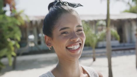 portrait of happy biracial woman smiling on sunny beach, in slow motion