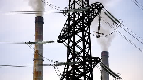 dark factory pipes against electrical pylons. factory pipes with smoke. dirty smoke pours out of chimneys into the air. aerial view video.