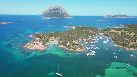 Isla-De-Porto-San-Paolo-Y-Tavolara-Rodeada-De-Barcos-Y-Mar-Azul-Turquesa-En-Cerdeña,-Italia---Antena-4k