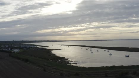puesta de sol amarilla y gris en la orilla de bradwell con barcos amarrados en silueta