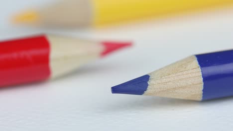 Three-Colored-Pencils-On-White-Background,-Focused-On-Blue-Pencil---macro