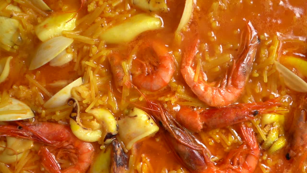 deliciosa fideuá de pescado hirviendo con gambas almejas y calamar vista superior