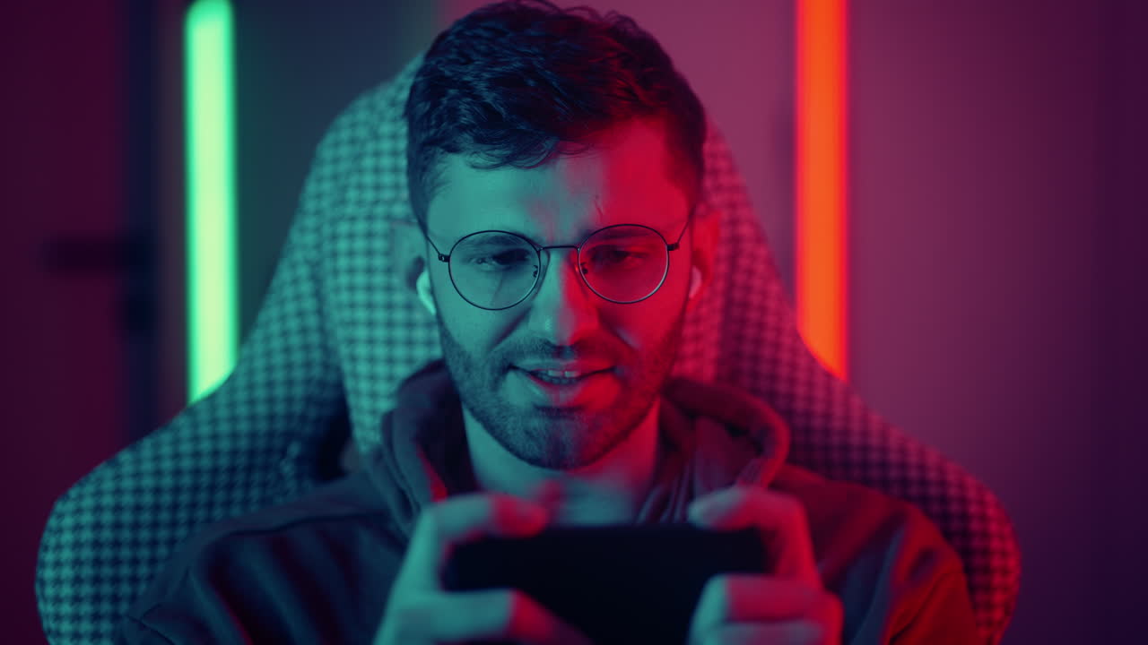 giocatore vincente in un videogioco su smartphone che sente gioia e felicità vincitore di un gioco mobile in un'app ritratto di gioioso giocatore con smartphone di notte a casa