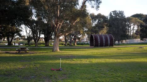 Toma-Panorámica-De-Un-Scooter-Y-Una-Bicicleta-Para-Niños-Abandonados-En-El-Parque-Público