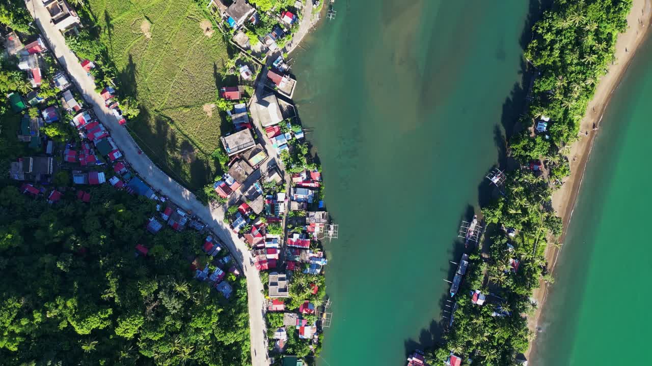 Aerial bird's eye view of a lush, tropical barangay village and bridge along estuary waters - Catanduanes, Bicol, Philippines