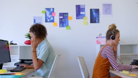 Seitenansicht-Von-Kaukasischen-Geschäftskollegen,-Die-An-Ihrem-Laptop-Arbeiten-Und-Ein-Audio-Headset-Verwenden,-Um-Zu-Sprechen