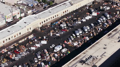 aerial view of a bustling outdoor market or logistics hub with numerous vehicles and goods