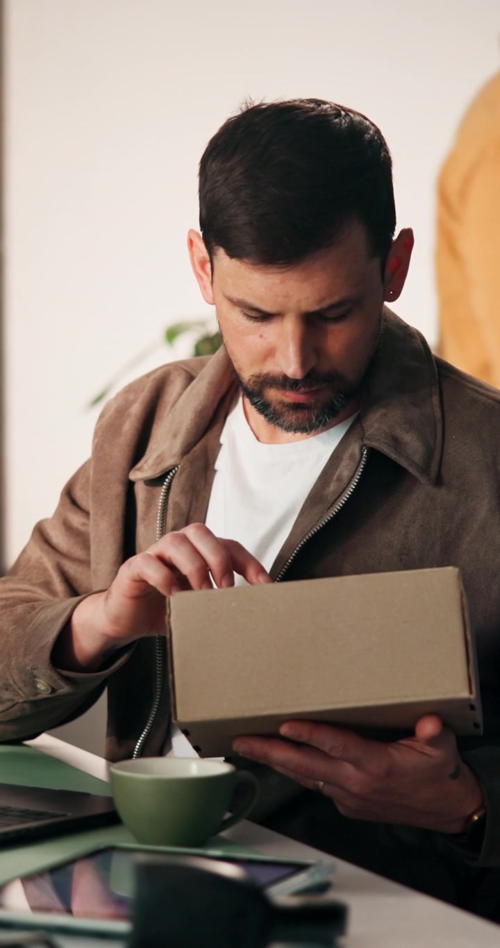Man Opening a Cardboard Package at His Desk