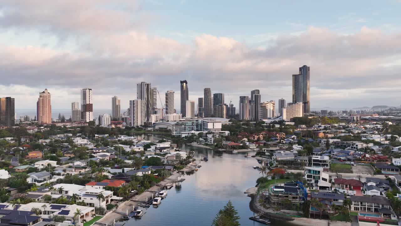 Smooth aerial flyover reveals Gold Coast skyline, residential canals, and waterfront homes at dusk