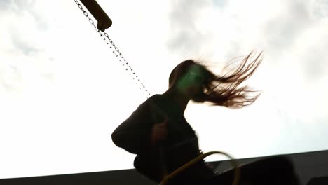 Low-angle-view-of-a-smiling-young-woman-swinging-and-looking-to-the-camera