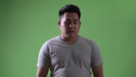 초록색 배경에 젊은 잘생긴 과체중 아시아인