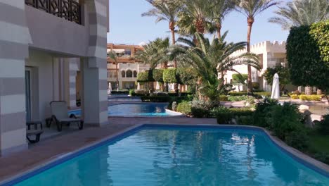 palm tree leaves and pool water surface beautiful summer tropical background through palm leaves on background.