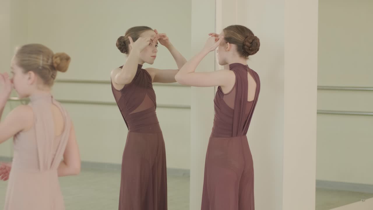 группа молодых студентов балета в черной танцевальной одежде практикует позиции в просторной балетной студии с деревянным полом и настенными решетками. сосредоточенные выражения и синхронизированные движения.