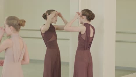 un grupo de jóvenes estudiantes de ballet con ropa de baile negra practicando posiciones en un amplio estudio de ballet con pisos de madera y barras montadas en la pared. expresiones enfocadas y movimientos sincronizados.