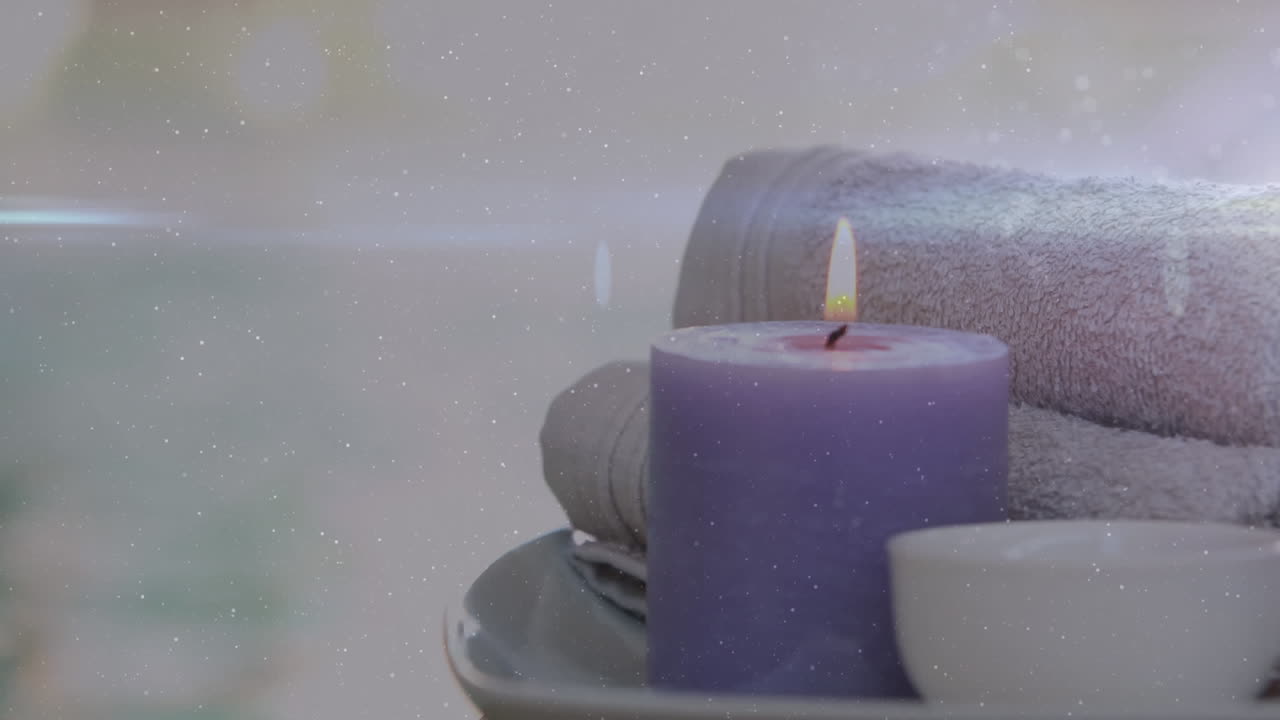 animación de luces sobre vela violeta, toallas y cuenco.