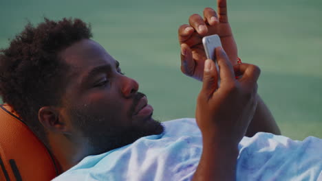 man relaxing outdoors with smartphone