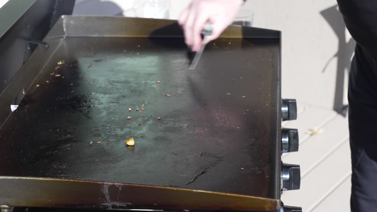 Scraping off the flat top griddle after cooking on it outside