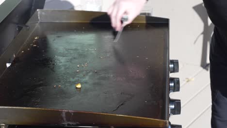scraping off the flat top griddle after cooking on it outside