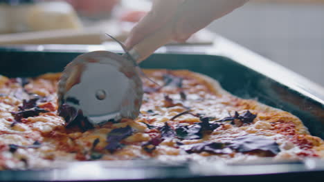 cutting freshly baked homemade pizza with pizza cutter