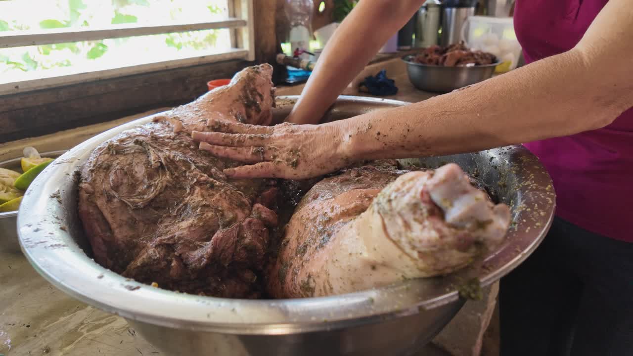 Close up of woman hands marinating pork leg with herbs and spices for roasting in rural Dominican Republic