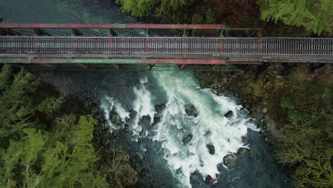 lewis river churns through rapids and flows under steel railroad bridge