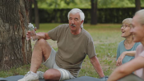 un hombre y una mujer mayores charlan después de hacer ejercicio al aire libre en el parque