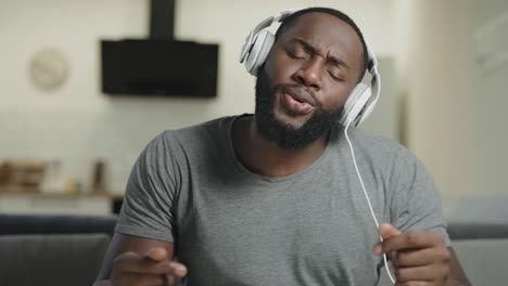 black man singing in headphones. portrait of happy guy dancing with body