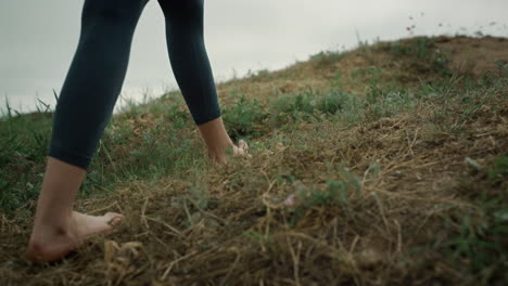 Unknown-woman-feet-walking-up-green-hill-close-up.-Girl-climbing-on-hilltop.