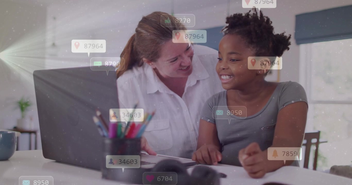 Mom leaning over girl at desk guiding study while she tapping laptop causing icons growing onscreen