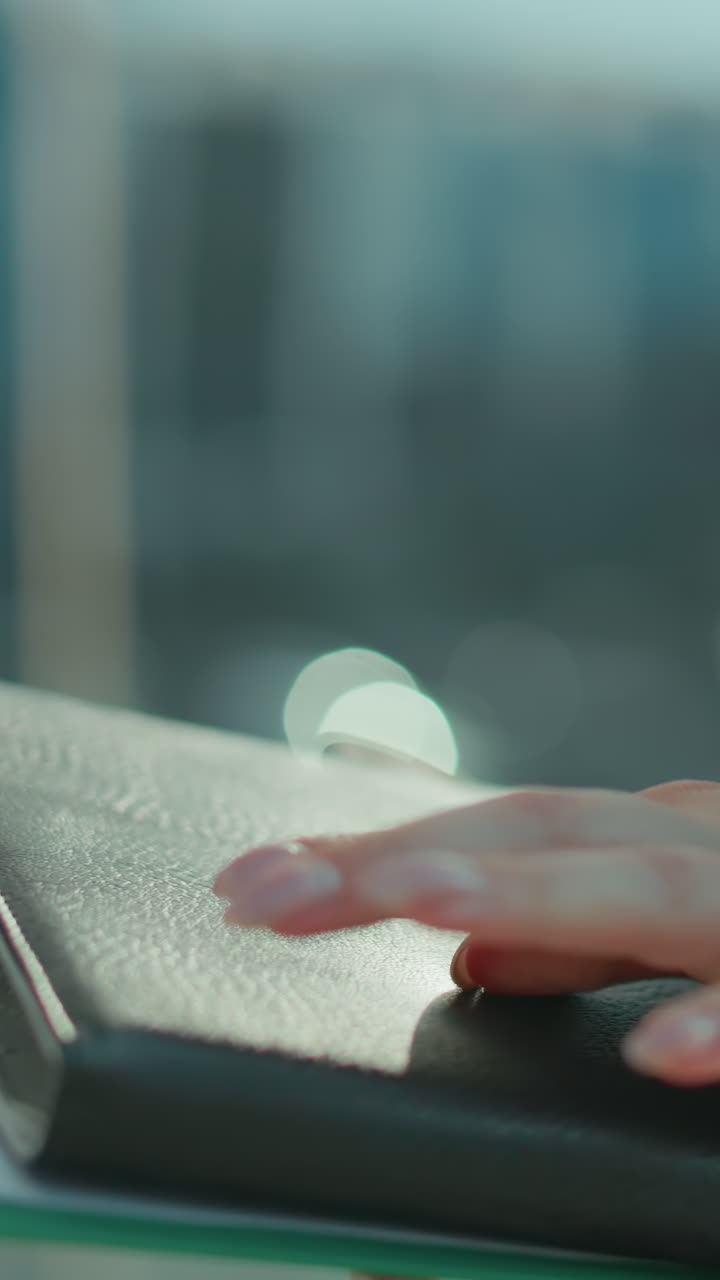 Close up of professional individual holding folder and documents, cross checking details while standing outdoors with glass building in background, focused on reviewing information