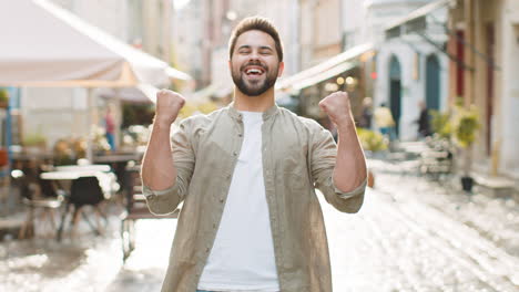 young man shouting, celebrating success winning goal achievement good victory news in city street