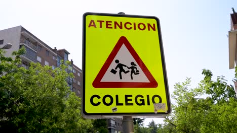 a spanish traffic sign warns drivers to be cautious. the yellow sign reads "atención colegio" (attention, school) and indicates a school zone where children may be present