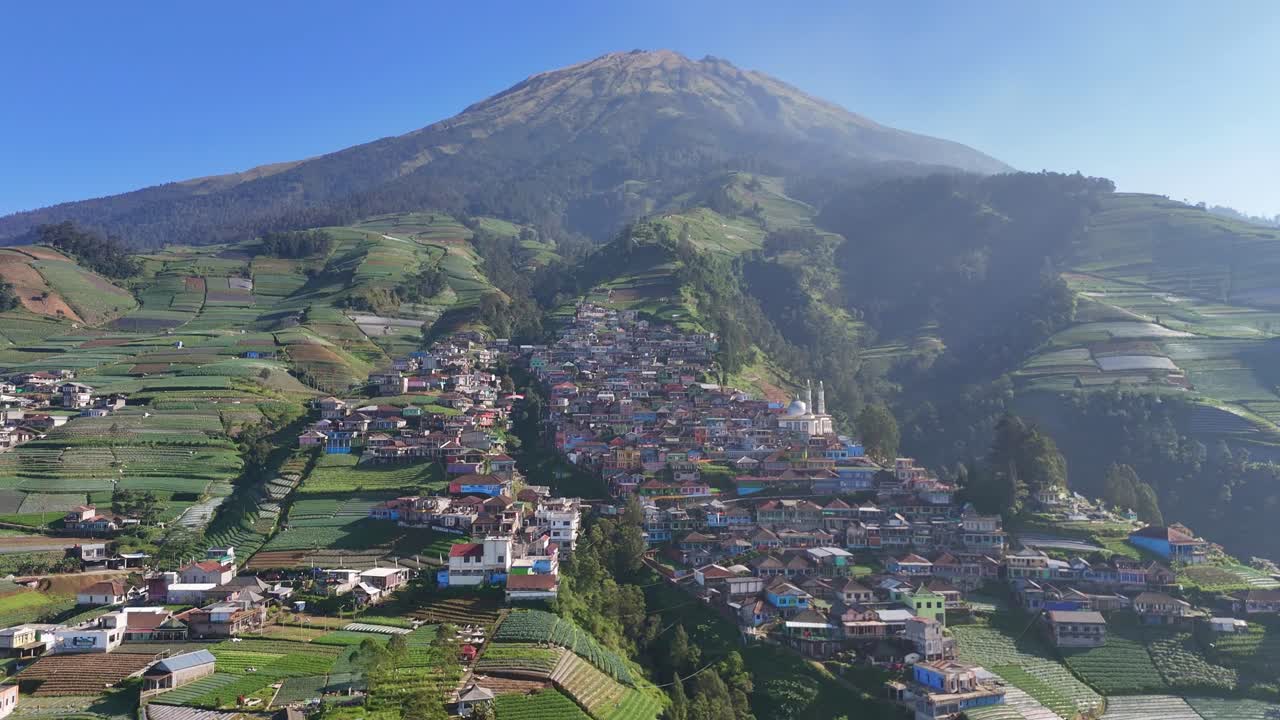 Panorama aereo di un villaggio agricolo di montagna, con file di colture e tetti colorati che si fondono nel paesaggio montano sotto la chiara luce del mattino. Nepal Van Java, Indonesia