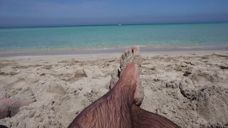 man relaxing barefoot on the beach looking at he sea | pov