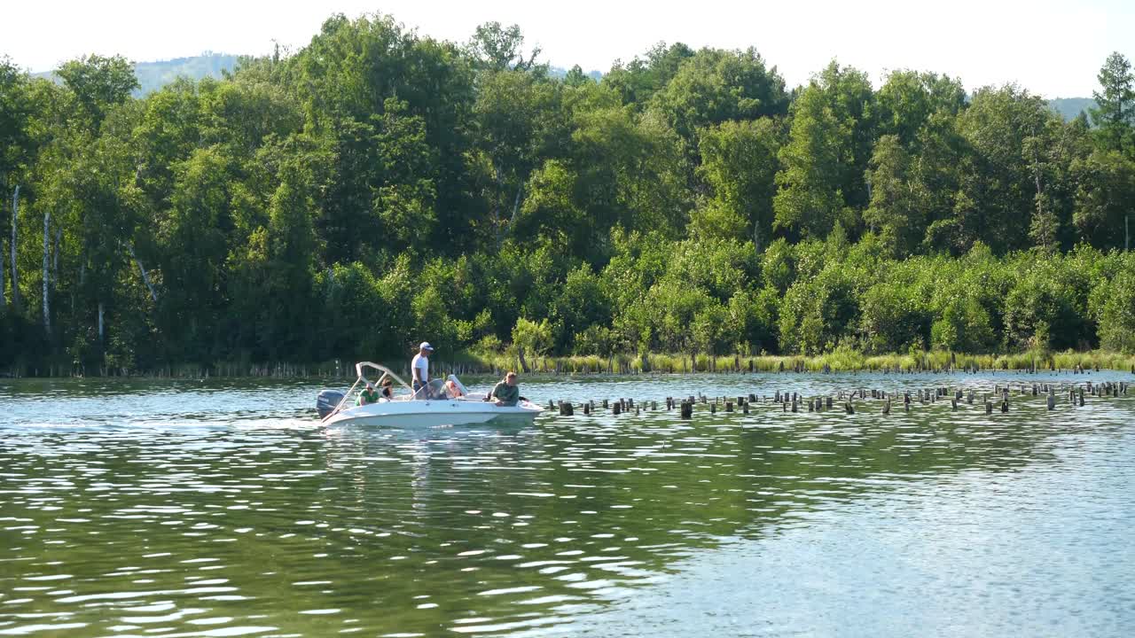 Folk i en motorbåd på en sø, omgivet af træer