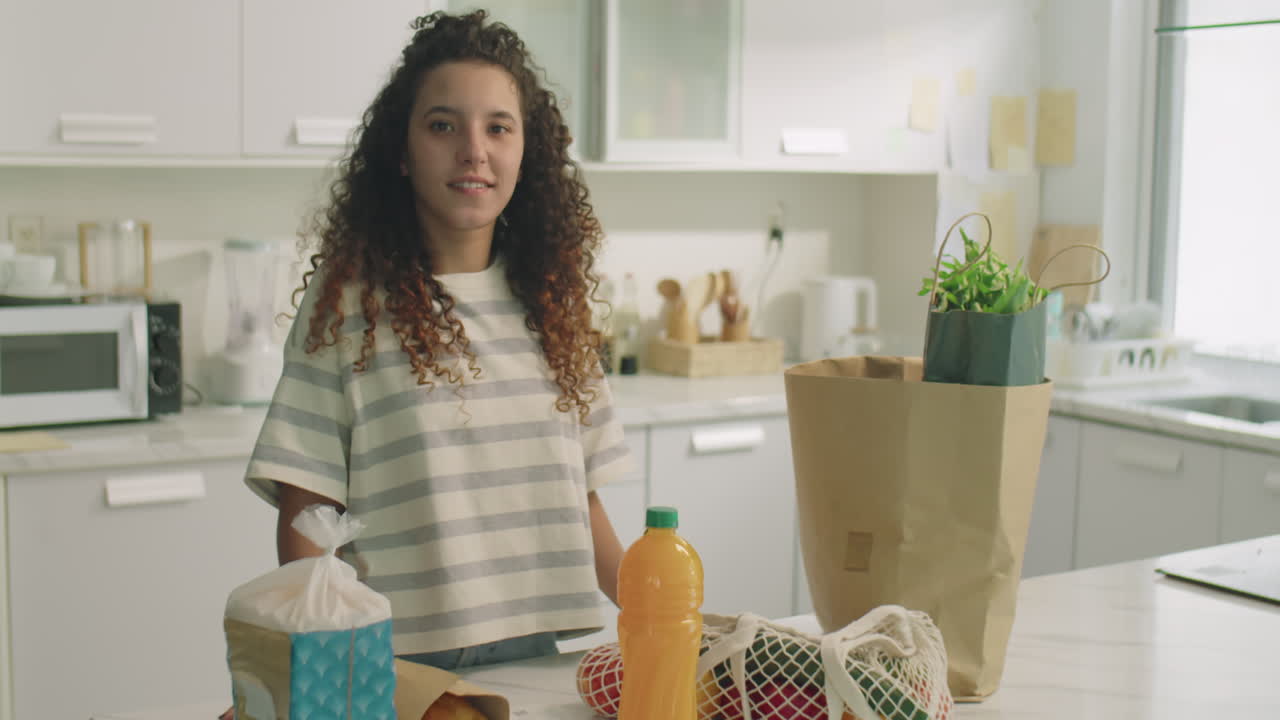 Portrait of Happy Girl by Kitchen Table with Groceries