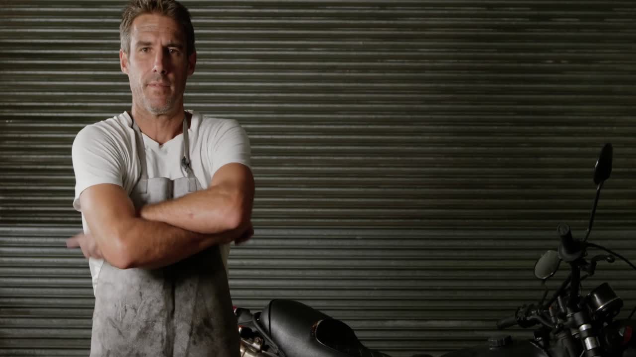 Male mechanic wearing apron in motorbike repair garage 4k