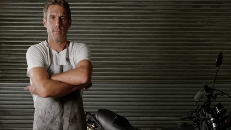 male mechanic wearing apron in motorbike repair garage 4k