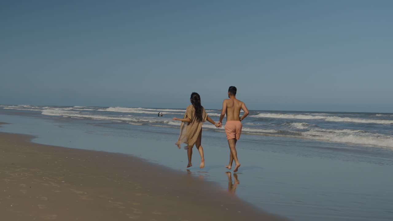 милая пара бегает по пляжу