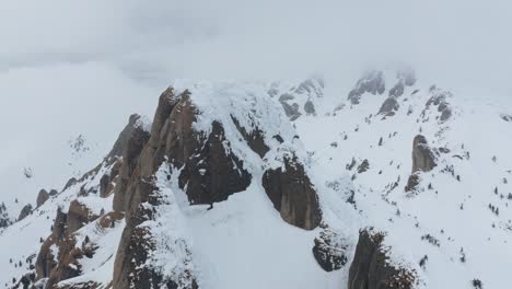 Snow-covered-ciucas-mountains-under-overcast-sky,-tranquil-nature-scene,-aerial-view