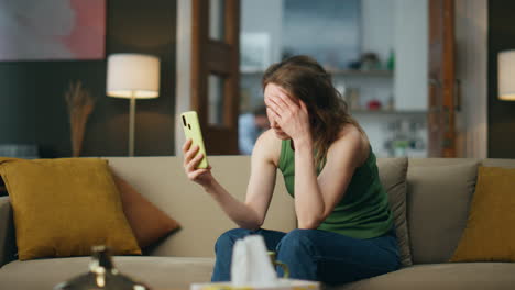 Mujer-Infeliz-Mirando-La-Pantalla-Del-Teléfono-En-La-Sala-De-Estar.-Niña-Triste-Recibiendo-Malas-Noticias