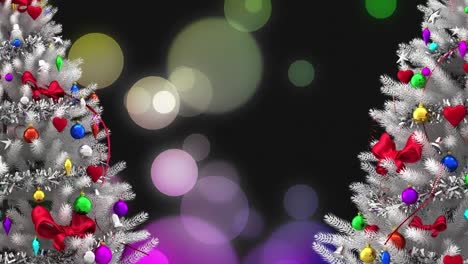 Animation-of-two-decorated-silver-christmas-trees-and-defocussed-lights-on-black-background