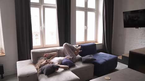 Young-caucasian-woman-in-pajamas-jumping-on-a-couch-running-from-the-stairs-at-home