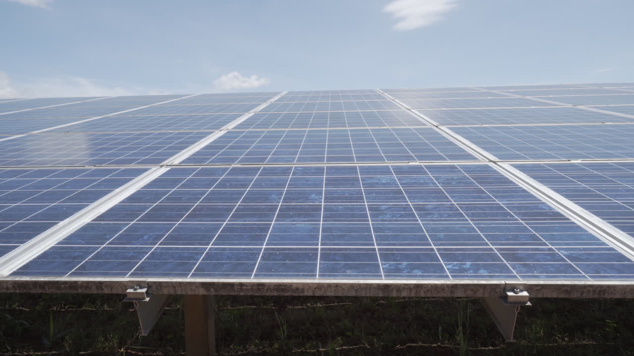 4k dolly pull in and out of the solar pv panel array inside a big solar power plant with lots of pv polycrystalline modules with clear blue sky
