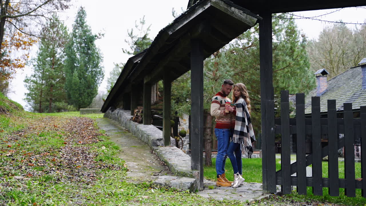 Couple in love in the countryside. Date of a romantic couple near the wooden gate of the cottage in autumn time.